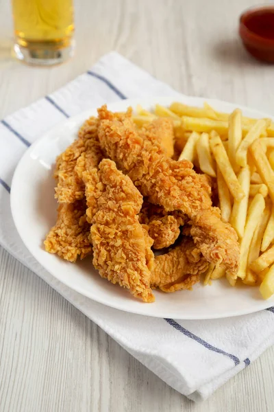 Homemade Crispy Chicken Tenders and French Fries with sauce and glass of cold beer, low angle view.