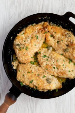 Ev yapımı İtalyan Tavuğu Piccata, dökme demir tavada, üst manzara. Yukarıdan, dümdüz uzanmış. 