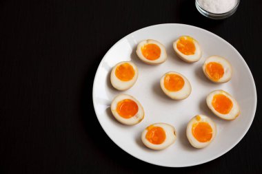 Siyah arka planda beyaz bir tabakta ev yapımı Unami Soya Sosu Yumurtası. Boşluğu kopyala.