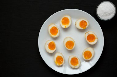 Ev yapımı Unami Soya Sosu Yumurtası, beyaz tabakta, siyah bir yüzey üzerinde, üst manzara. Yukarıdan, dümdüz yatıyordu. Boşluğu kopyala.