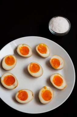 Ev yapımı Unami Soya Sosu Siyah arka planda beyaz bir tabakta, yan görünüm. 