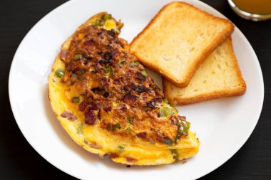 Siyah arka planda beyaz bir tabakta ev yapımı Denver omleti..