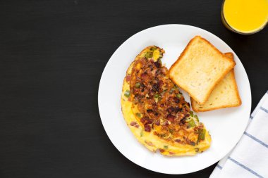 Siyah arka planda beyaz tabakta ev yapımı Denver omleti, üst manzara. Dümdüz, tepeden, yukarıdan. Boşluğu kopyala.