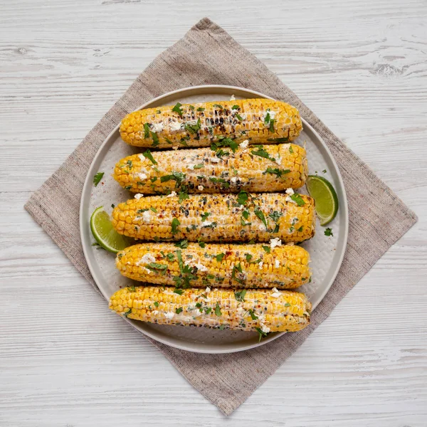 Beyaz ahşap arka planda bir tabakta ev yapımı Meksika sokak mısırı, üst manzara. Dümdüz, tepeden, yukarıdan. 