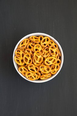 Gri bir kasede çıtır kraker, siyah bir yüzey, üst manzara. Dümdüz, tepeden, yukarıdan.