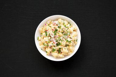 Beyaz kasede siyah arka planda ev yapımı makarna salatası. Dümdüz, tepeden, yukarıdan. 
