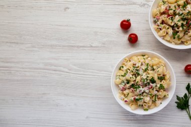 Beyaz ahşap arka planda beyaz kaselerde ev yapımı makarna salatası, üst manzara. Dümdüz, tepeden, yukarıdan. Boşluğu kopyala.