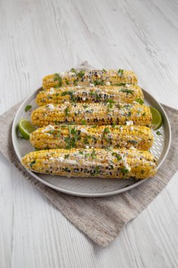 Beyaz ahşap bir arka planda beyaz bir tabakta ev yapımı Meksika sokak mısırı.. 