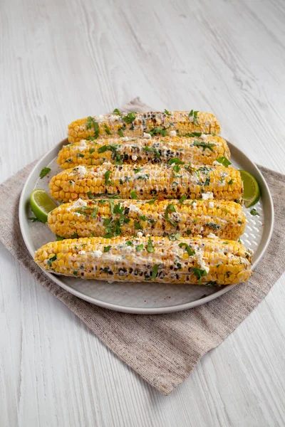 Beyaz ahşap bir arka planda beyaz bir tabakta ev yapımı Meksika sokak mısırı.. 