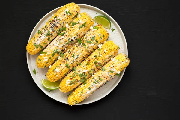 Ev yapımı Meksika sokak mısırı, siyah arka planda bir plaka, üst manzara. Dümdüz, tepeden, yukarıdan. Metin için boşluk.