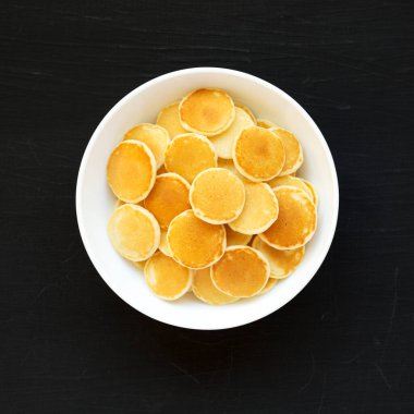 Siyah arka planda beyaz bir kasede ev yapımı Mini Krep Gevreği. Dümdüz, tepeden, yukarıdan. 