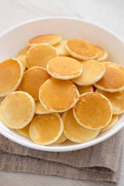 Beyaz ahşap arka planda beyaz bir kâse içinde ev yapımı Mini Krep Gevreği. Yakın plan..