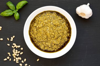 Siyah bir yüzeye parmesanlı ve çam fıstıklı ev yapımı Basil Pesto. Dümdüz, tepeden, yukarıdan.