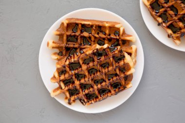 Gri arka planda beyaz bir tabakta nefis ev yapımı Belçika şekerli waffle 'ları. Dümdüz, tepeden, yukarıdan. 