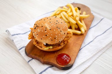 Patates kızartmalı ev yapımı tavuk şeritli burger ve ekşi tatlı soslu köy panosu, yan görüş..
