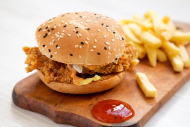 Patates kızartmalı ev yapımı tavuk şeritli burger ve ekşi tatlı soslu köy panosu, yan görüş.. 