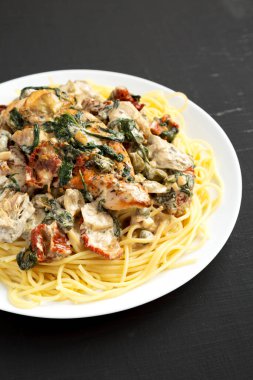 Siyah bir yüzey üzerinde beyaz bir tabakta makarna ile ev yapımı kremalı Toskana tavuğu.. 