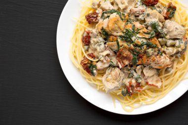 Siyah arka planda beyaz bir tabakta makarna ile ev yapımı kremalı Toskana tavuğu. Boşluğu kopyala.