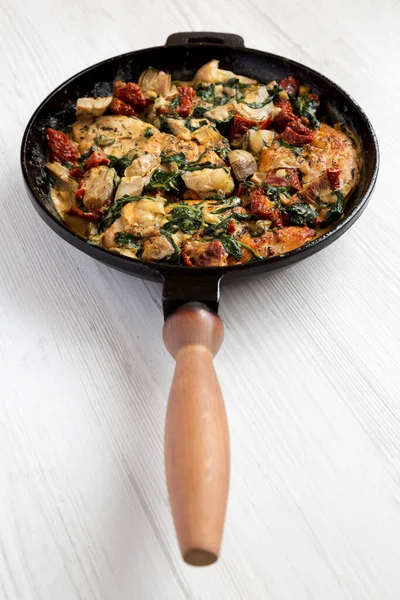 Beyaz ahşap arka planda dökme demir tavuklu ev yapımı kremalı Toskana tavuğu. Düşük açılı.. 