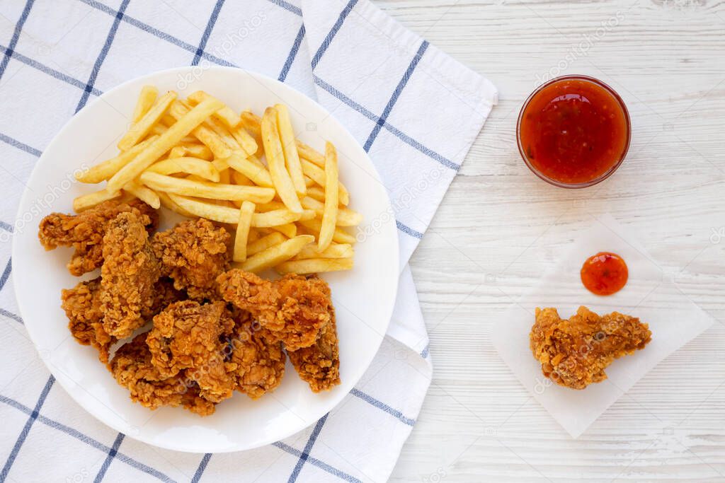 Homemade Crispy Chicken wings and French Fries with sour-sweet sauce on a white wooden background, top view. From above, overhead, flat lay.