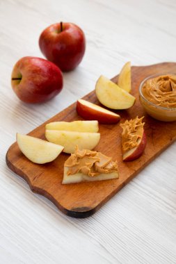 Beyaz ahşap bir yüzey üzerinde çiğ kırmızı elmalar ve fındık ezmesi.. 