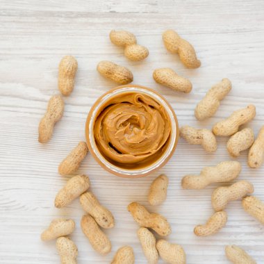 Fıstık ezmesi dolu kavanoz beyaz ahşap bir masa, üst manzara. Dümdüz, tepeden, yukarıdan. 