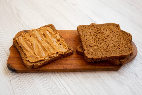 Stück Brot Mit Erdnussbutter Auf Rustikalem Holzbrett Auf Weißem Holzhintergrund — Stockfoto