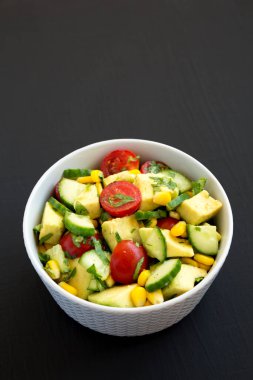 Siyah arka planda bir kasede taze Avocado Domates Salatası, üst manzara. Dümdüz, tepeden, yukarıdan. Boşluğu kopyala.