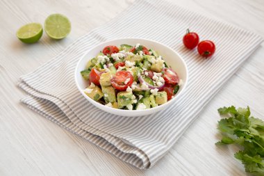 Lezzetli Avokado Domates ve salatalık salatası beyaz ahşap arka planda bir kasede, yan görünüm. 