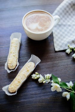 Kapuçino, eklerleri ve çiçekler.