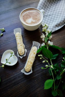 Kapuçino, eklerleri ve çiçekler.