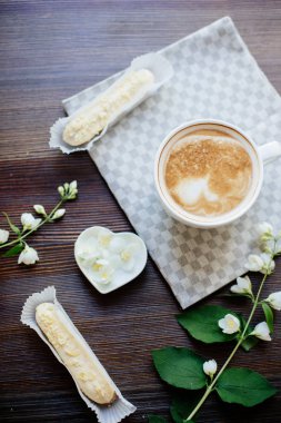 Kapuçino, eklerleri ve çiçekler.