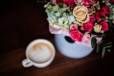 Fincan kapuçino ve çiçekler.