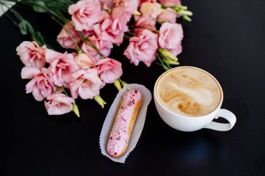 Kapuçino, eklerleri ve çiçekler.