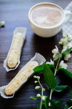 Kapuçino, eklerleri ve çiçekler.