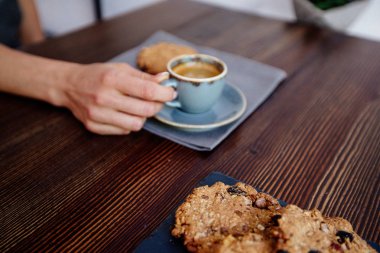 Fincan kahve ve kurabiye elinde.