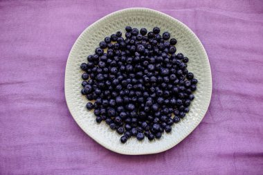 Renkli bir bezle bir masaya bir tabak içinde yaban mersini.