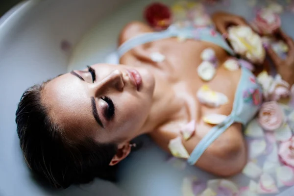 Beautiful girl in the bathroom with many flowers. — Stock Photo, Image