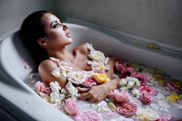 Vacker flicka i badrummet med många blommor. — Stockfoto