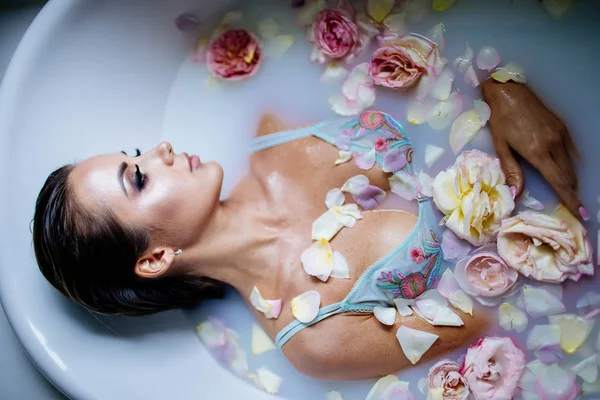 Beautiful girl in the bathroom with many flowers. — Stock Photo, Image