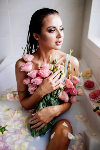 Beautiful girl in the bathroom with many flowers. — Stock Photo, Image