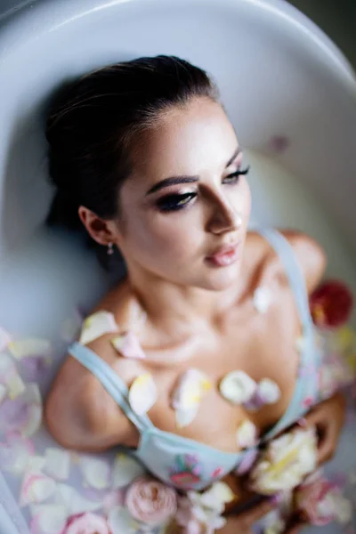 Beautiful girl in the bathroom with many flowers. — Stock Photo, Image