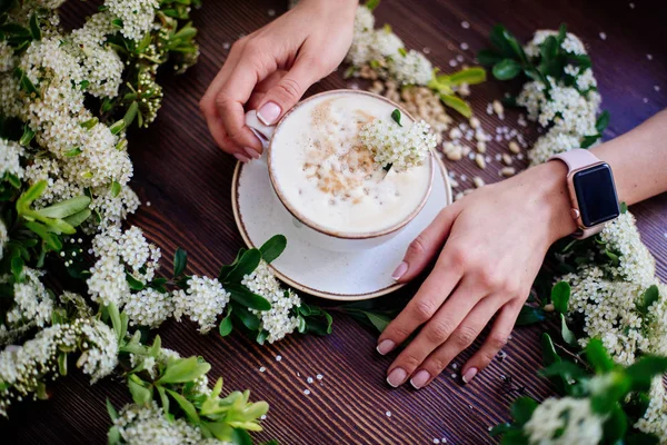 Coffee in hand and white flowers.