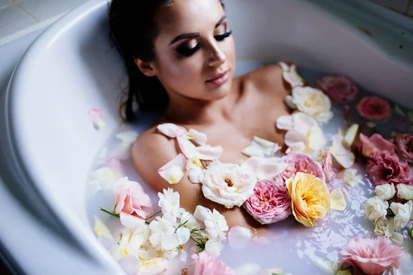 Beautiful girl in the bathroom with many flowers. — Stock Photo, Image