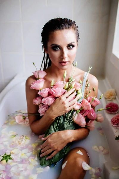 Beautiful girl in the bathroom with many flowers. — Stock Photo, Image