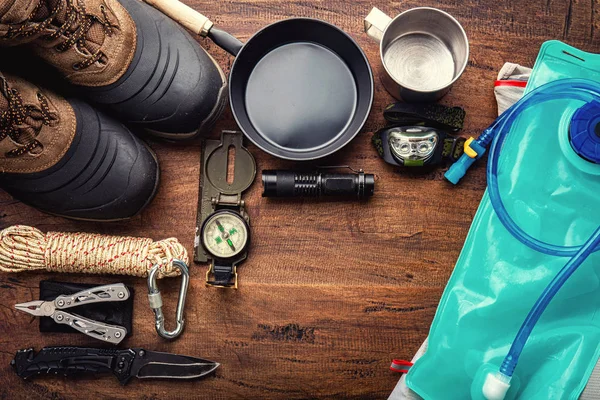 Ahşap arka plan üzerinde bir dağ trekking kamp gezisi için açık hava seyahat ekipmanları planlama. Üstte görüntüle - vintage film tane filtresi efekt stilleri