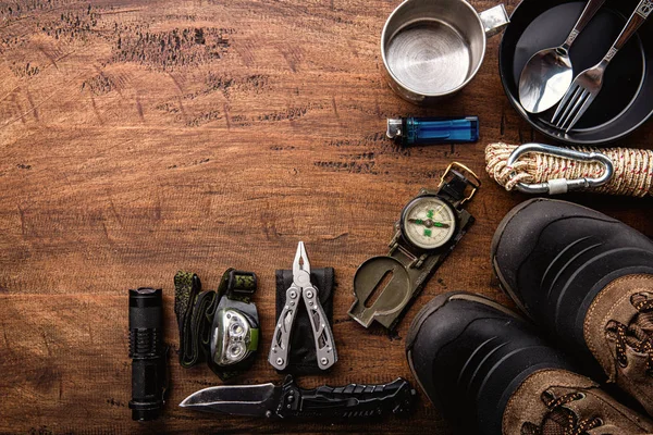 Outdoor travel equipment planning for a mountain trekking camping trip on wooden background. Top view - vintage film grain filter effect styles