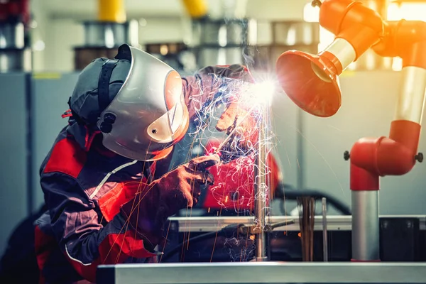 Industrial welder worker is welding metal part in factory with p