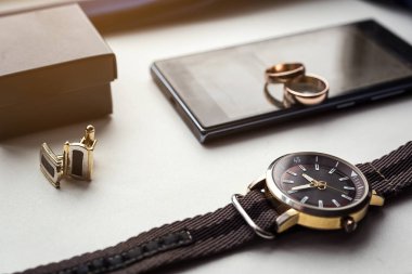 Farklı Erkek aksesuarlar gibi: kol düğmeleri, saatler, yüzük ve telefon - masada vardır