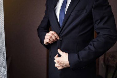 İş adamı ceket giyiyor, erkek eli kapalı, damat düğün töreninden önce hazırlanıyor.